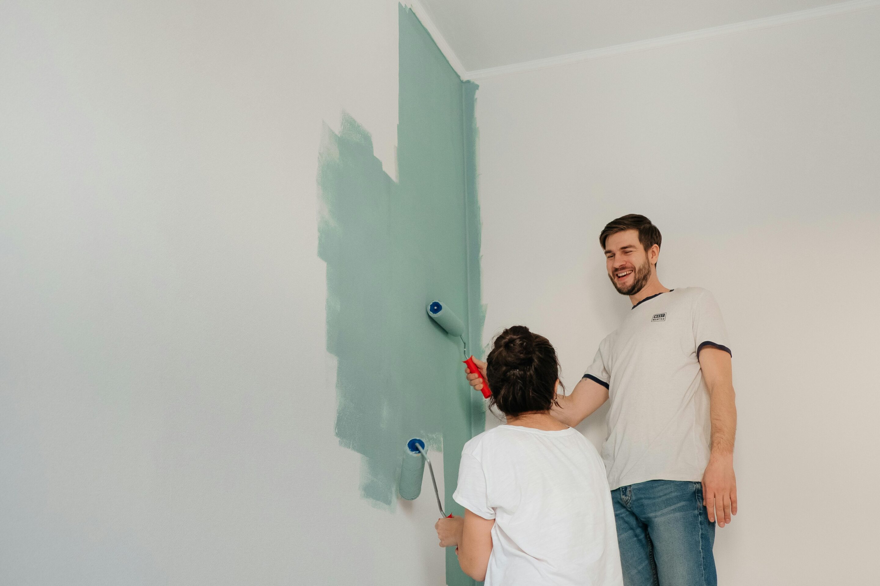 Two people painting a wall green