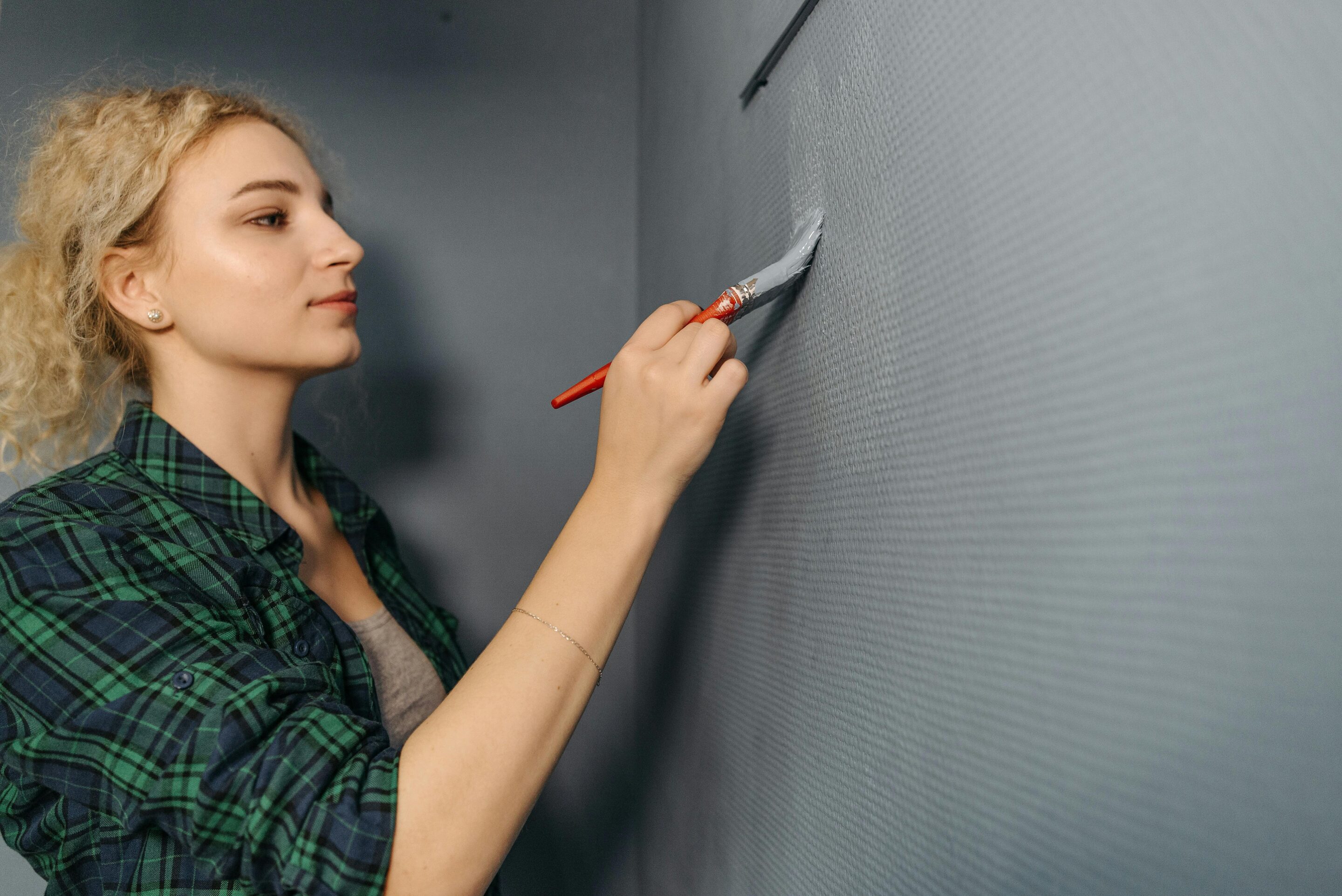 A woman painting a wall with a brush